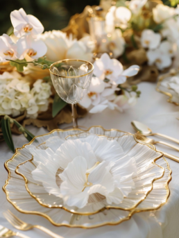 Elegant white and gold dining table setting with floral accents and exquisite glassware.