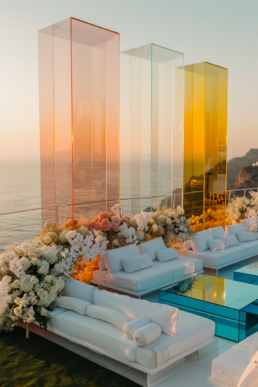 Luxurious outdoor lounge with floral accents, elegant glass columns, and a stunning sunset view.