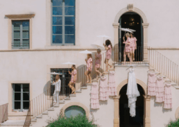 Young women in pink outfits celebrate a bridal party outside a charming villa.