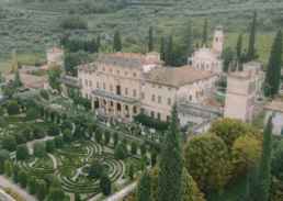 Elegant estate garden with historical villa, manicured hedges, and picturesque Italian countryside.
