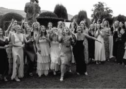 Celebratory wedding moment with joyous women in elegant dresses amidst a beautiful garden.