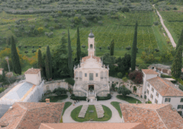 Elegant villa wedding venue amidst lush gardens and vineyards in picturesque Italian landscape.